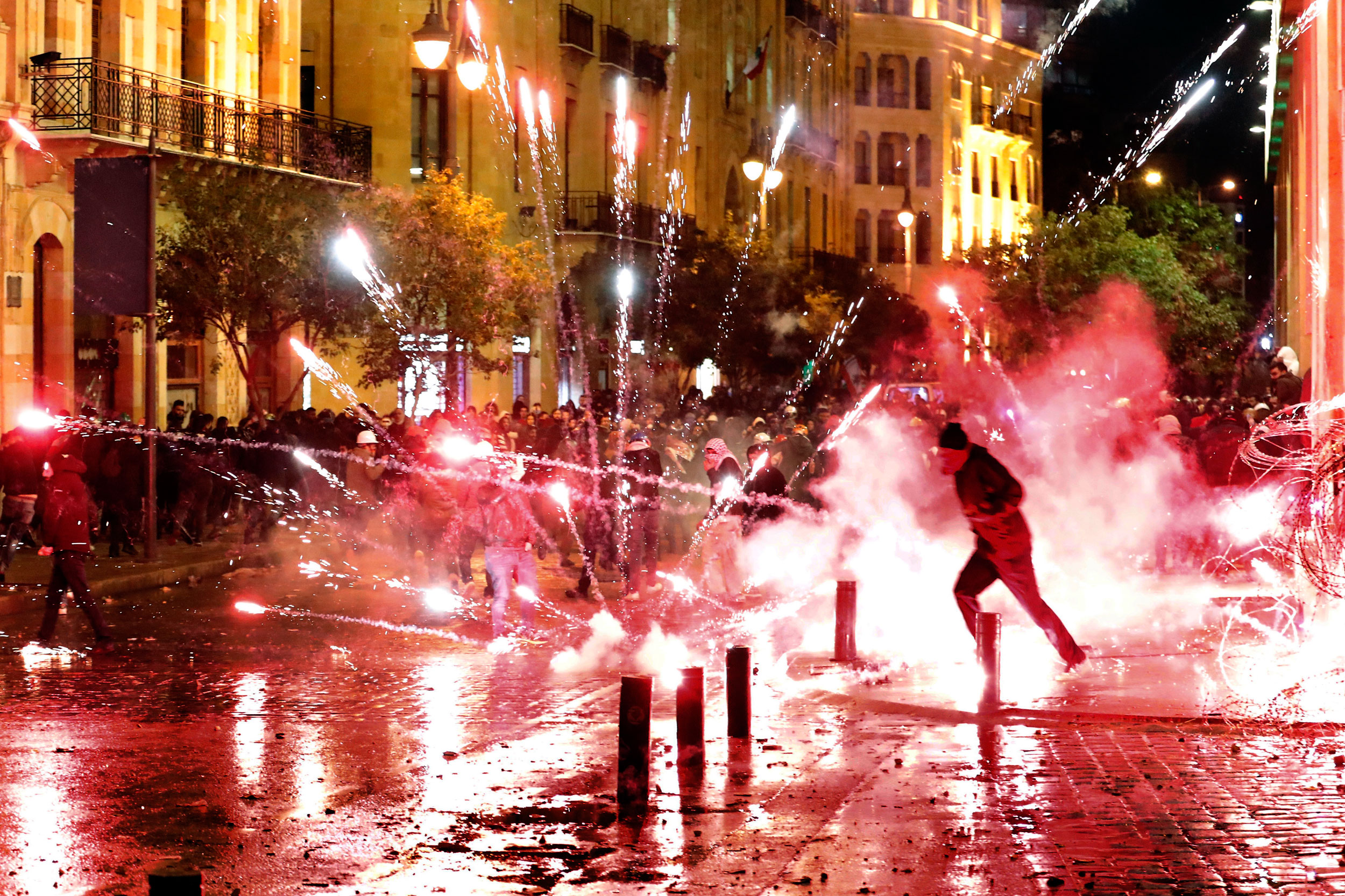 Anti-government protesters throw firecrackers at riot police during a demonstration against the new government, near Parliament Square, in Beirut, on Wednesday.