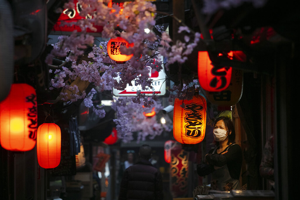 A cook wearing a mask stands outside a restaurant Thursday, March 26, 2020, in Tokyo. Japan's Prime Minister Shinzo Abe is setting up a special task force to discuss coronavirus measures and emergency responses as the government now considers the spread of the COVID-19 virus rampant in the country, officials said Thursday.