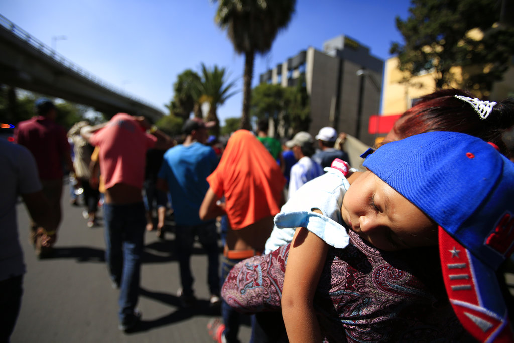 A sleeping Honduran girl is carried as Central American migrants march to the office of the United Nations' humans rights body in Mexico City.