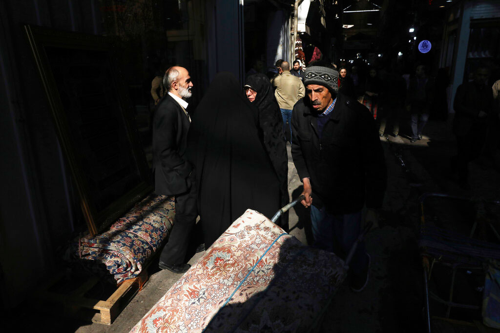 A man carries a rug at the Grand Bazaar in Tehran, Iran, on Thursday. A new budget designed to resist crippling US trade embargoes was presented to the Iranian parliament on Sunday, as the country aims to depend less on oil revenue next year.