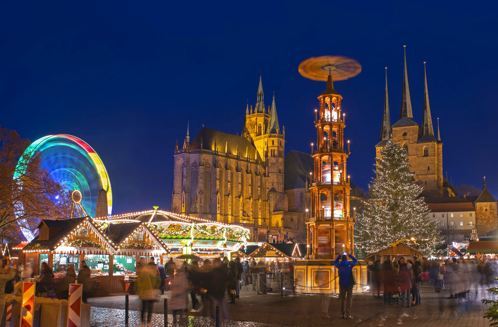 In this picture taken with a long time exposure people walk along the Christmas Fair in front of the Mariendom (Cathedral of Mary) and St. Severi's Church in Erfurt, central Germany. The Erfurt Christmas Market is one of the most beautiful Christmas Markets in the whole of Germany. The square is beautifully decorated with a huge, candle-lit Christmas tree and a large, hand-carved wooden creche.
