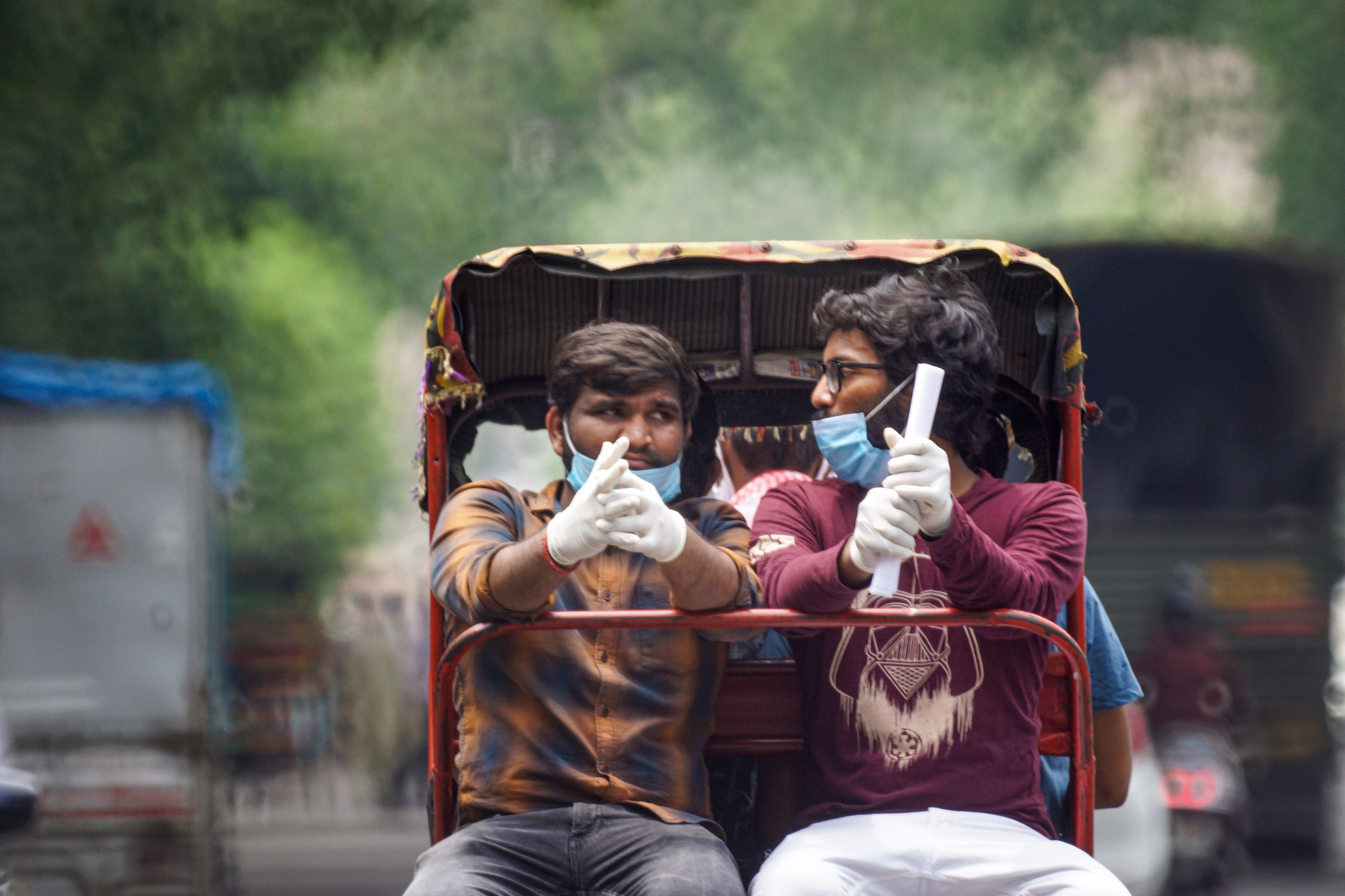  Masked men travel on a cycle rickshaw in New Delhi