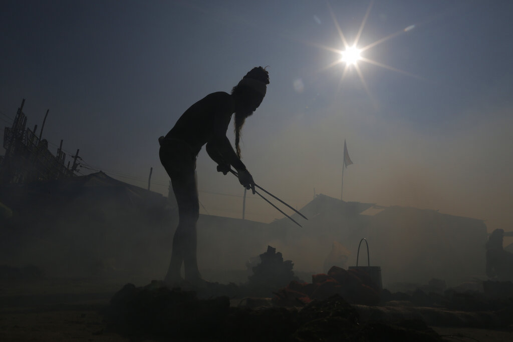 A Hindu holy man performs a ritual by burning dried cow dung cakes in earthen pots at Sangam, the confluence of the rivers Ganges, Yamuna, and mythical Saraswati, at the annual traditional fair of Magh Mela in Prayagraj