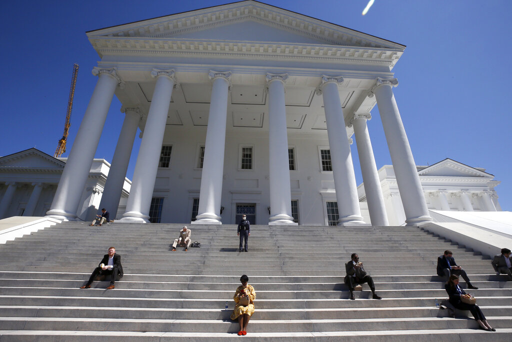 House of Delegates members eat boxed lunches on the steps of the Virginia State Capitol in Richmond, Va., before the veto session began Wednesday, April 22, 2020. The House members were meeting outside in a tent instead of the House Chamber in order to practice social distancing due to the coronavirus.