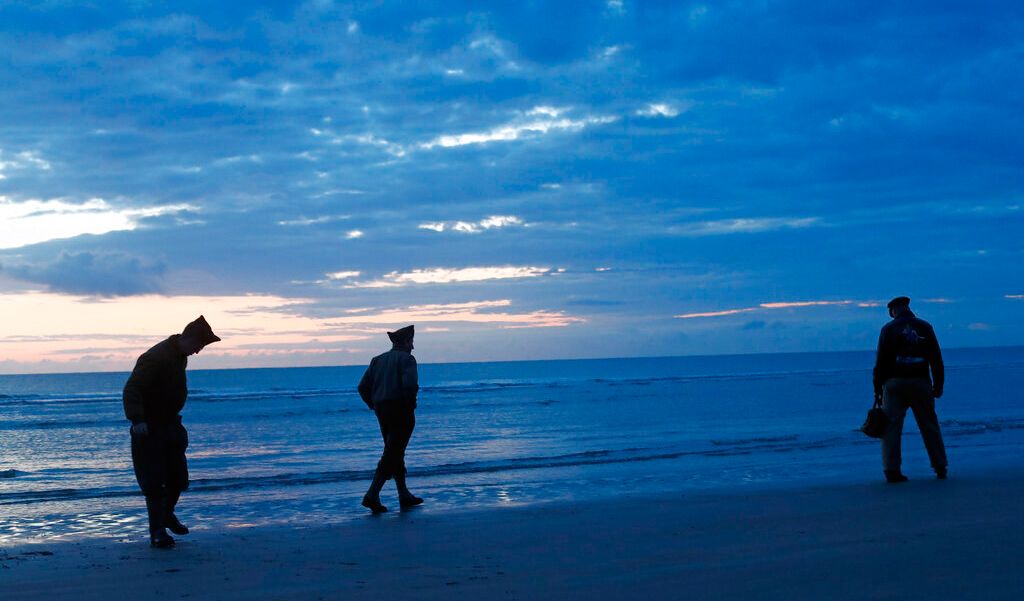 World War II re-enactors walk along Omaha Beach, in Normandy, France, at dawn on Thursday, June 6, 2019 during commemorations of the 75th anniversary of D-Day.