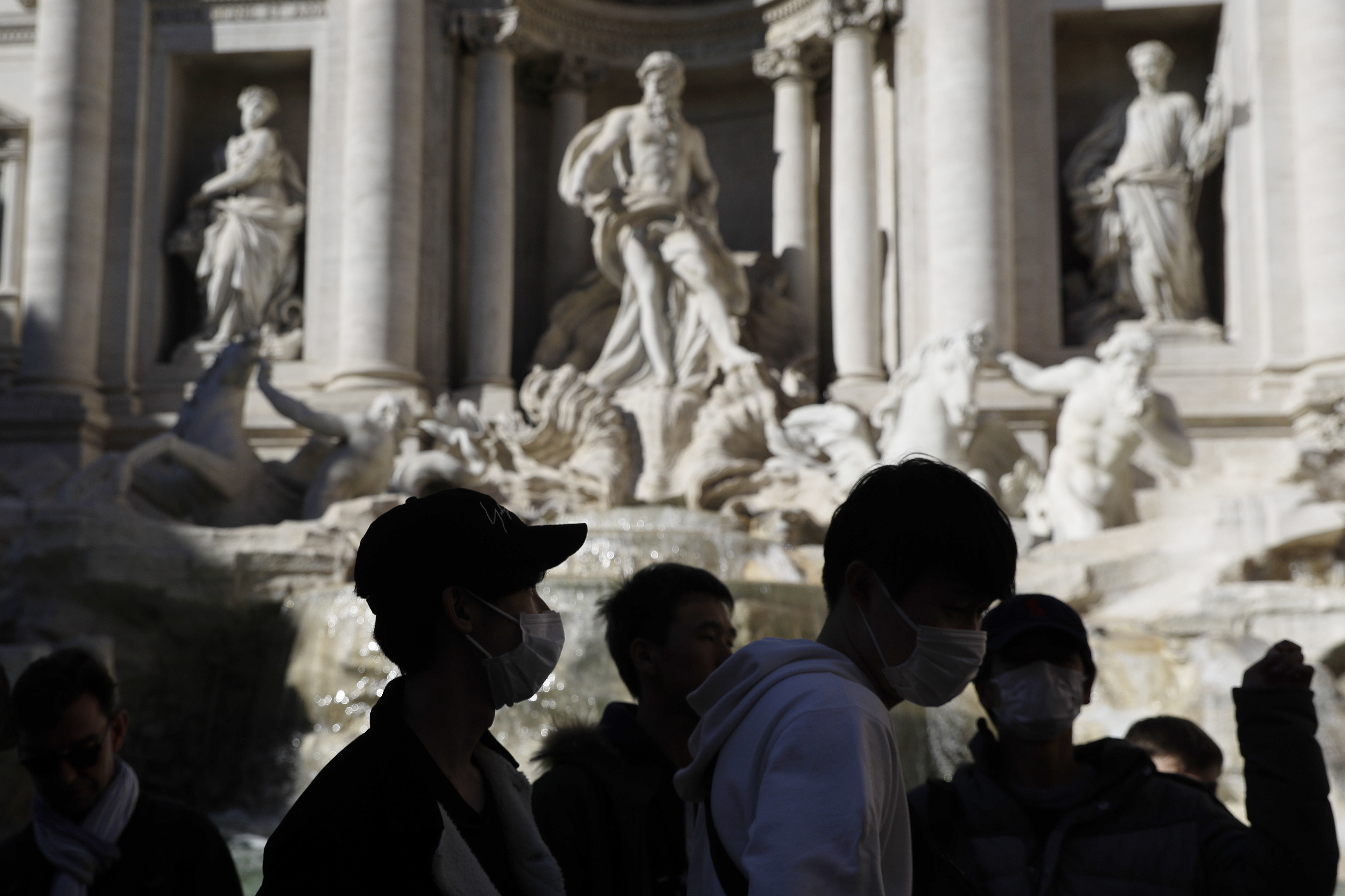 Tourists wear face masks as they gather at the Trevi fountain in Rome on Friday