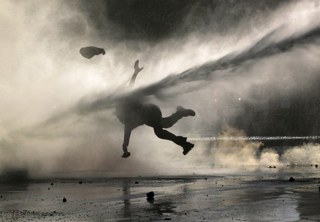 An anti-government demonstrator is sprayed by a police water cannon during a protest in Santiago, Chile, on Monday. Student protests have become a nationwide call for socio-economic equality and better social services, so far forcing Chilean President Sebastian Pinera to increase benefits for the poor and disadvantaged and start a process of constitutional reform.