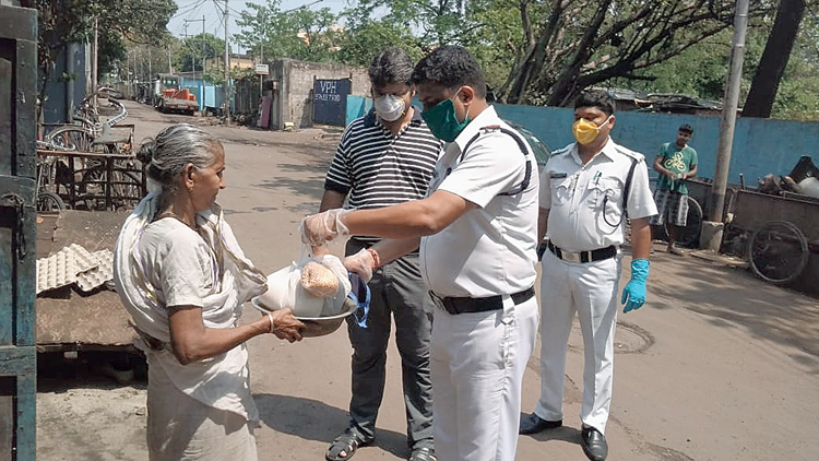 A police officer hands over essential items to a woman in Sinthee