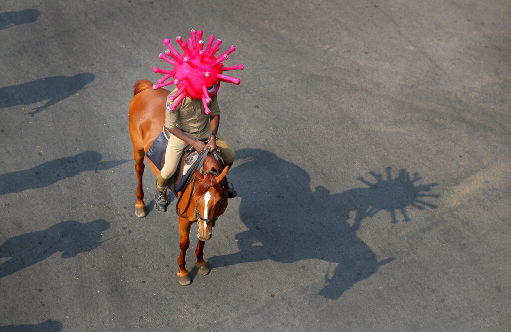A policeman wearing a virus themed helmet rides on a horse during an awareness rally aimed at preventing the spread of new coronavirus in Hyderabad, on Thursday, April 2, 2020.