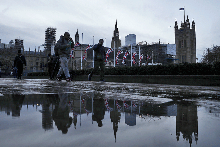 Pedestrians walk past the Palace of Westminster in London.
