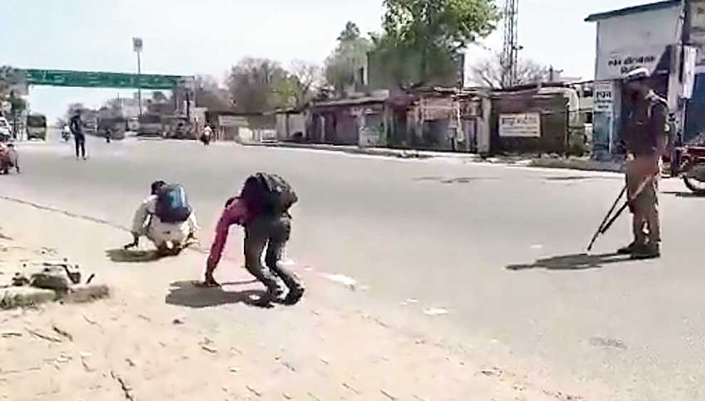 Youths are made to hop on the road by policemen for violating prohibitory orders during the lockdown in Badaun on Thursday. 