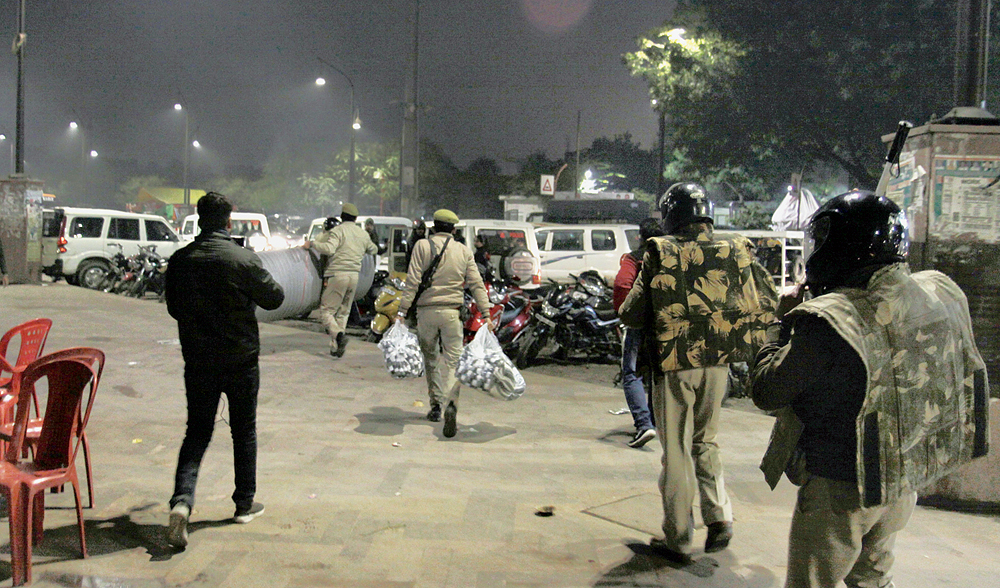 Policemen, who held a march around the Ghanta Ghar in Lucknow on Saturday evening, walk away with blankets, mattresses and other material that volunteers had brought for the women and children protesters