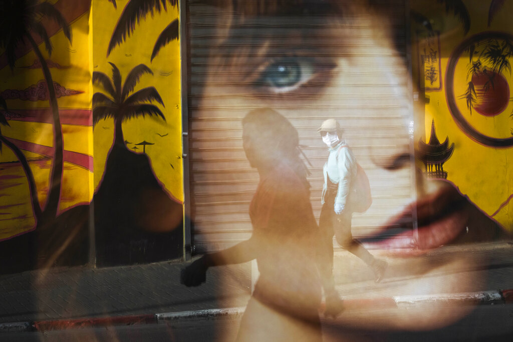 A woman is reflected on a bus station as she wears a protective face mask amid concerns over the country's coronavirus outbreak, in Tel Aviv, Israel, on Monday