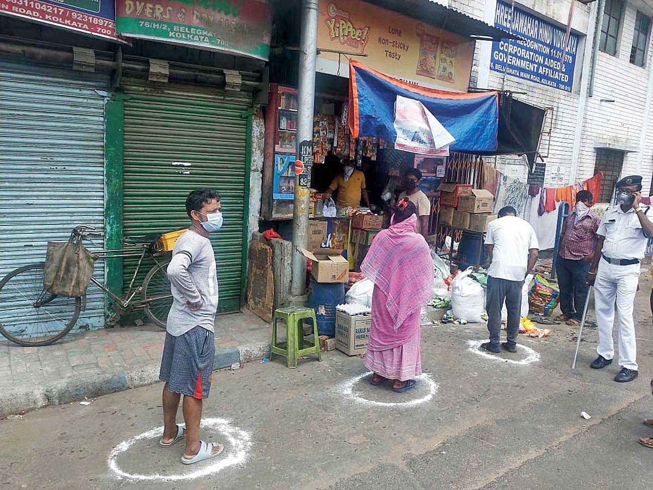 People stand inside circles in a queue in front of a medicine shop in Beleghata on Wednesday. The circles were drawn by police to ensure social distancing.