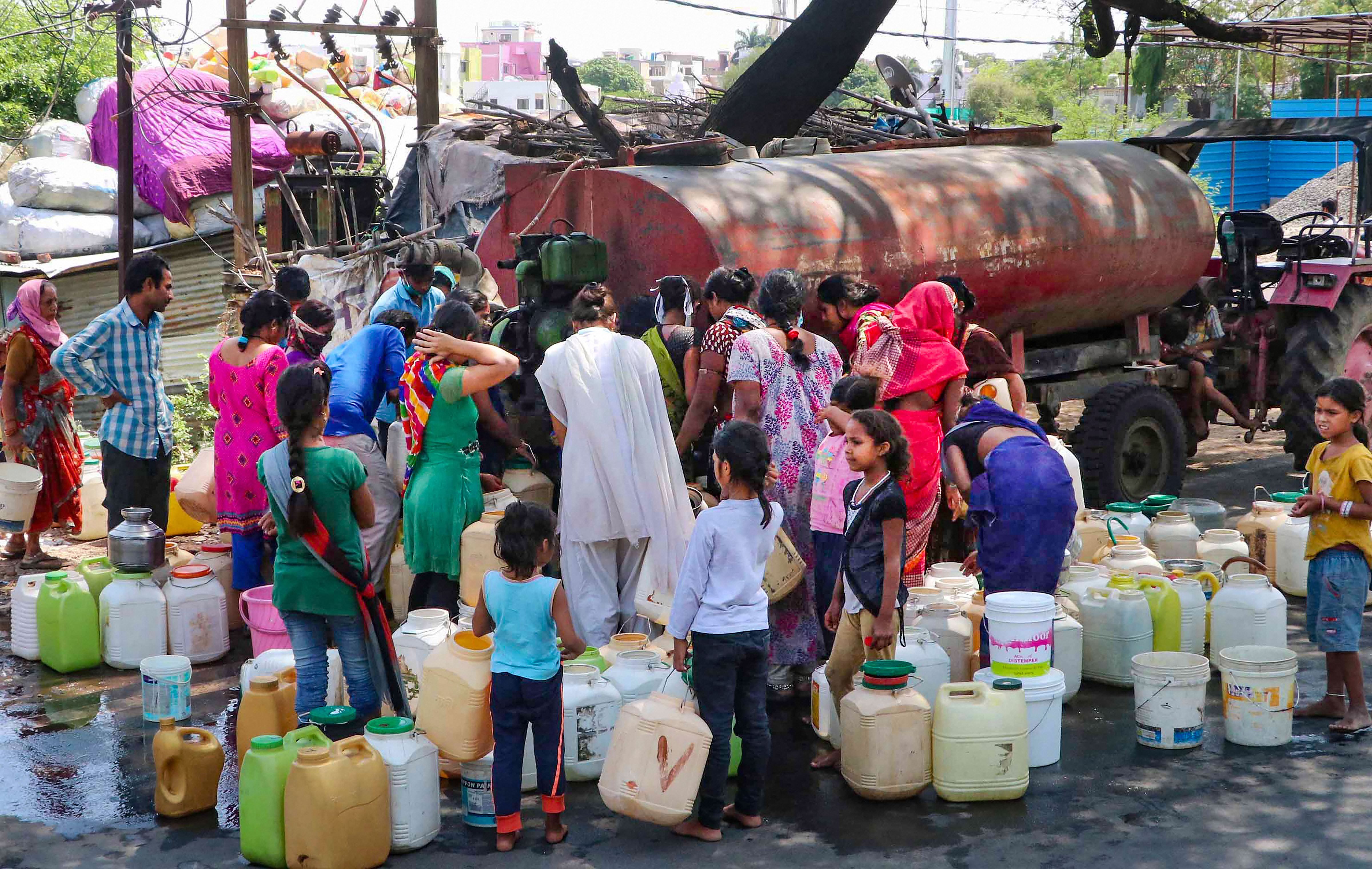 People violate social distancing norms as they fill their vessels with drinking water from a BMC water tanker, during the nationwide lockdown to curb the spread of coronavirus, in Bhopal, Wednesday, April 22, 2020. 