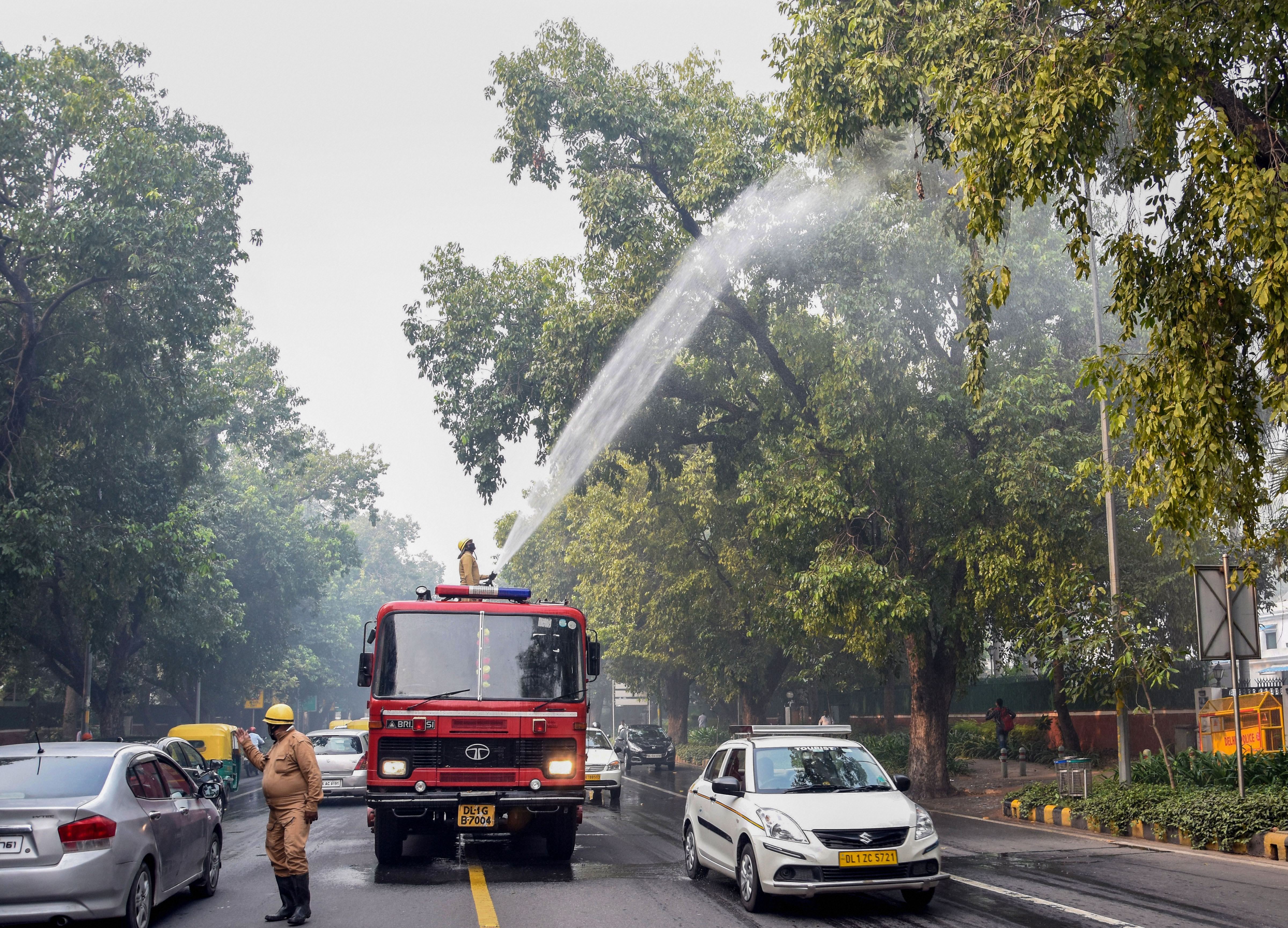 A NDMC fire service personnel sprays water on trees to curb the growing pollution in New Delhi, Wednesday, November 13, 2019.