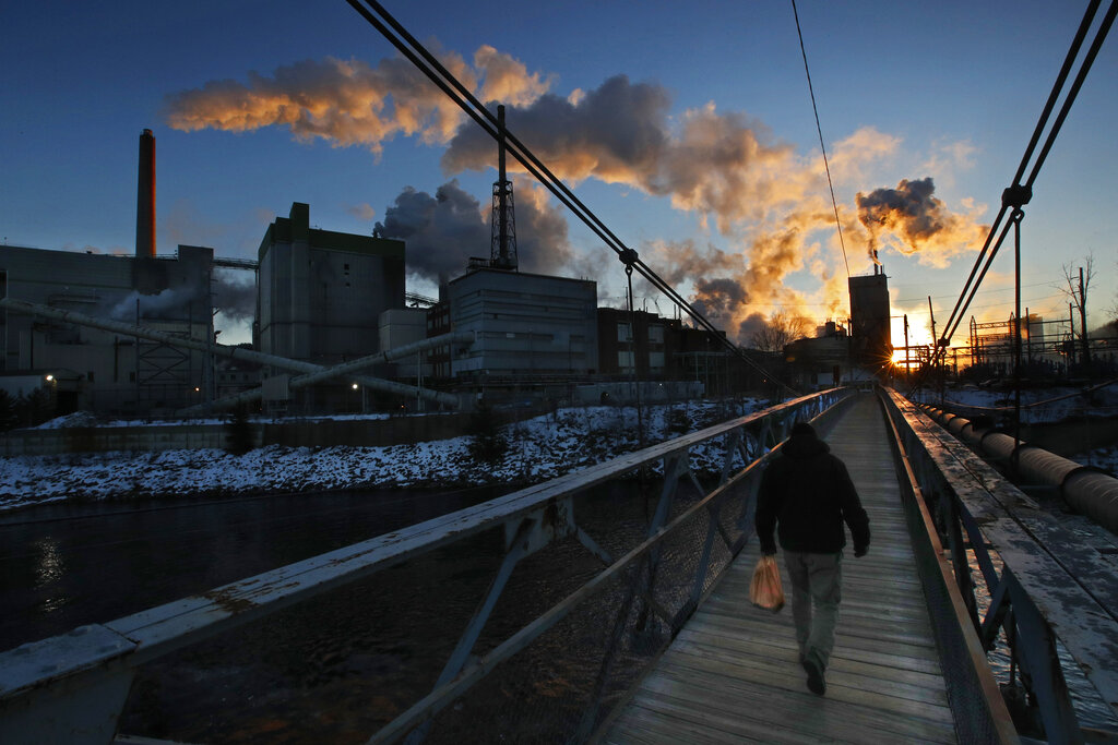 A worker crosses a pedestrian bridge on his way to work a shift at the ND Paper mill, on Thursday