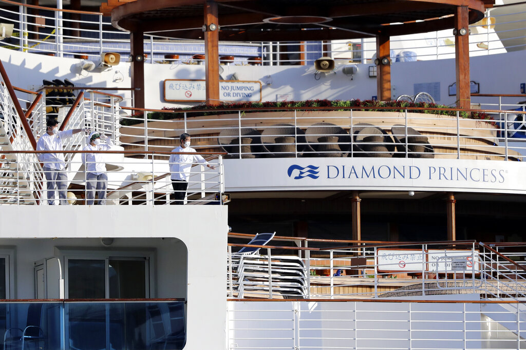 Crews stand on the deck the quarantined Diamond Princess cruise ship anchored at a port in Yokohama on Friday