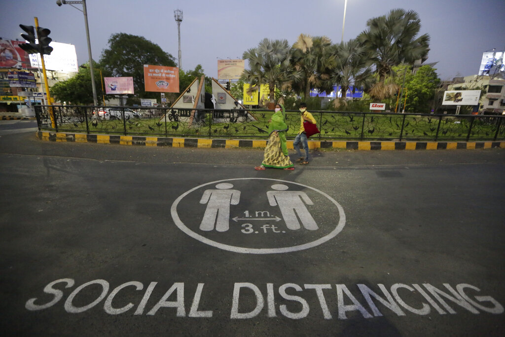 A woman and a boy walk past an awareness message painted on road during lockdown to control the spread of the new coronavirus in Ahmedabad, on Thursday, April 23, 2020.