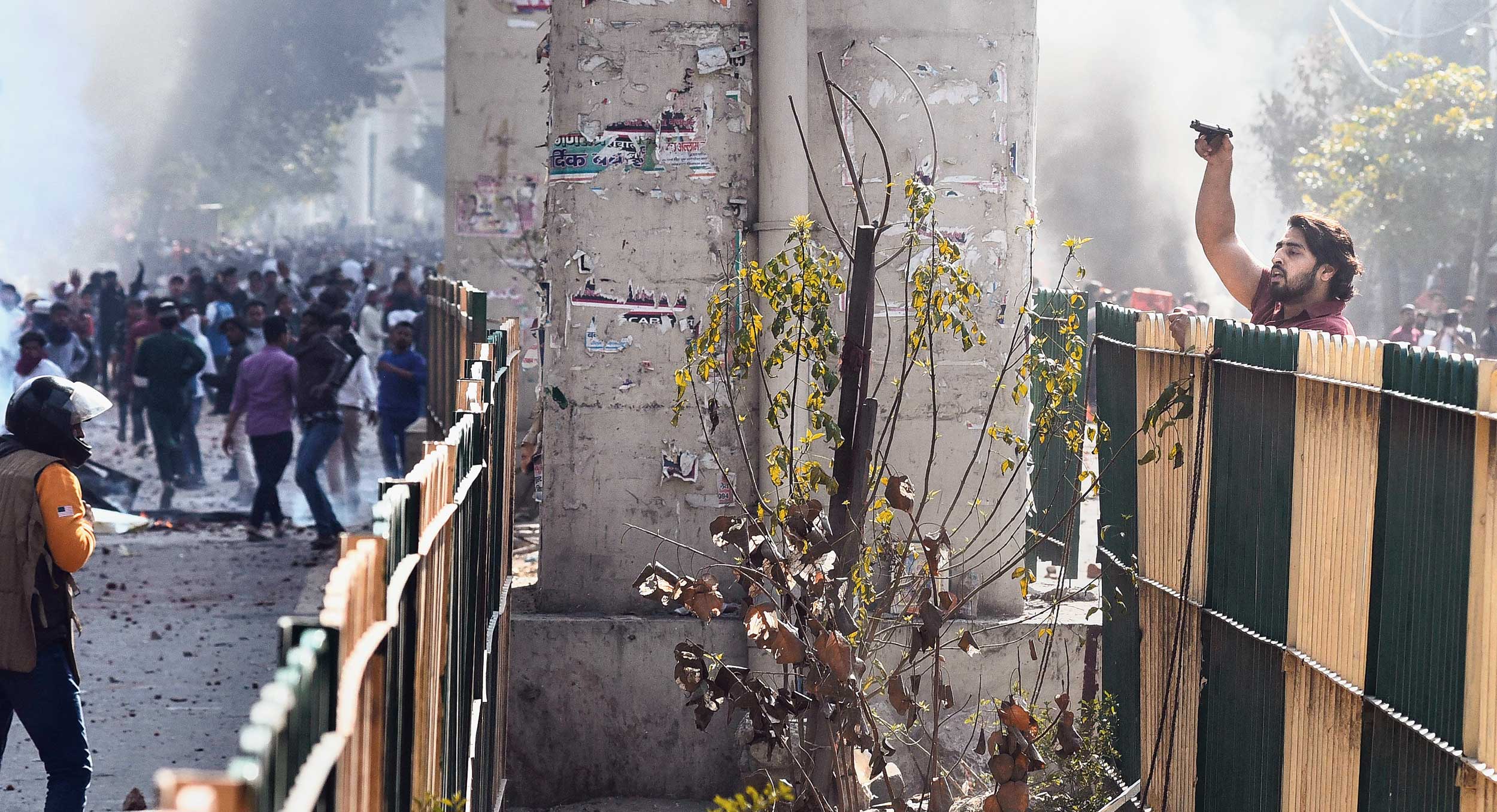 A man brandishes a pistol during a clash in New Delhi on Monday.