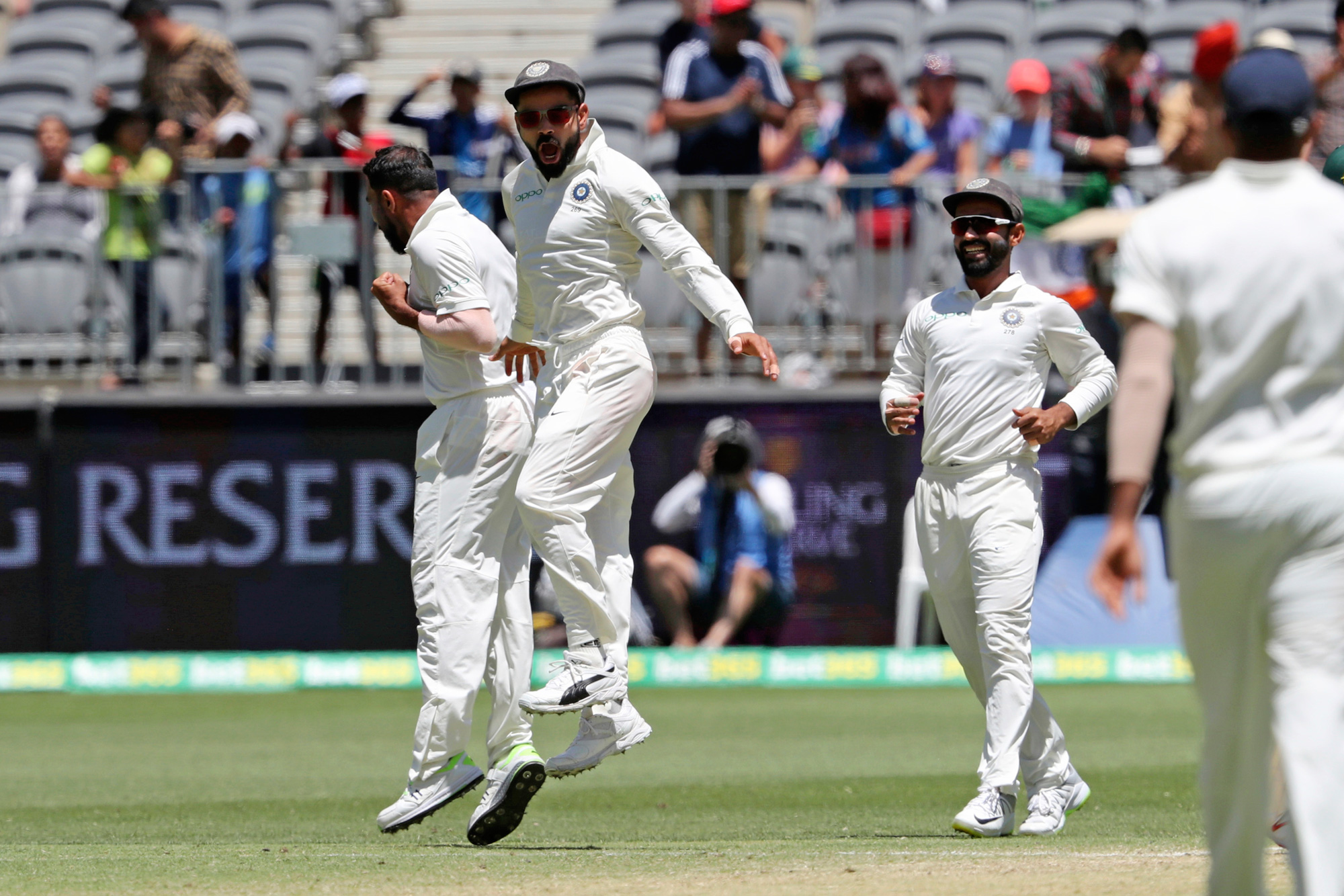 India's Mohammed Shami, left, and Virat Kohli leap as they celebrate the dismissal of Australia's Aaron Finch during play in the second cricket test between Australia and India in Perth, Australia, on Monday, December 17, 2018.