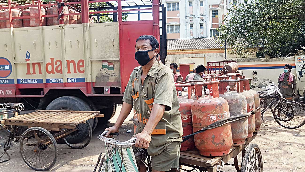 Sujit Naskar cycles out of the godown at Sarat Abasan with gas cylinders
