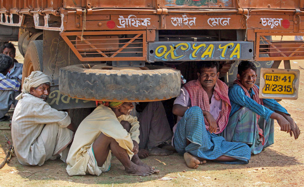 Migrants rest under a truck on NH-60 near Illambazar while waiting to travel back to their native places in Jharkhand, during the ongoing Covid-19 nationwide lockdown, in Birbhum district, Tuesday, May 19, 2020.