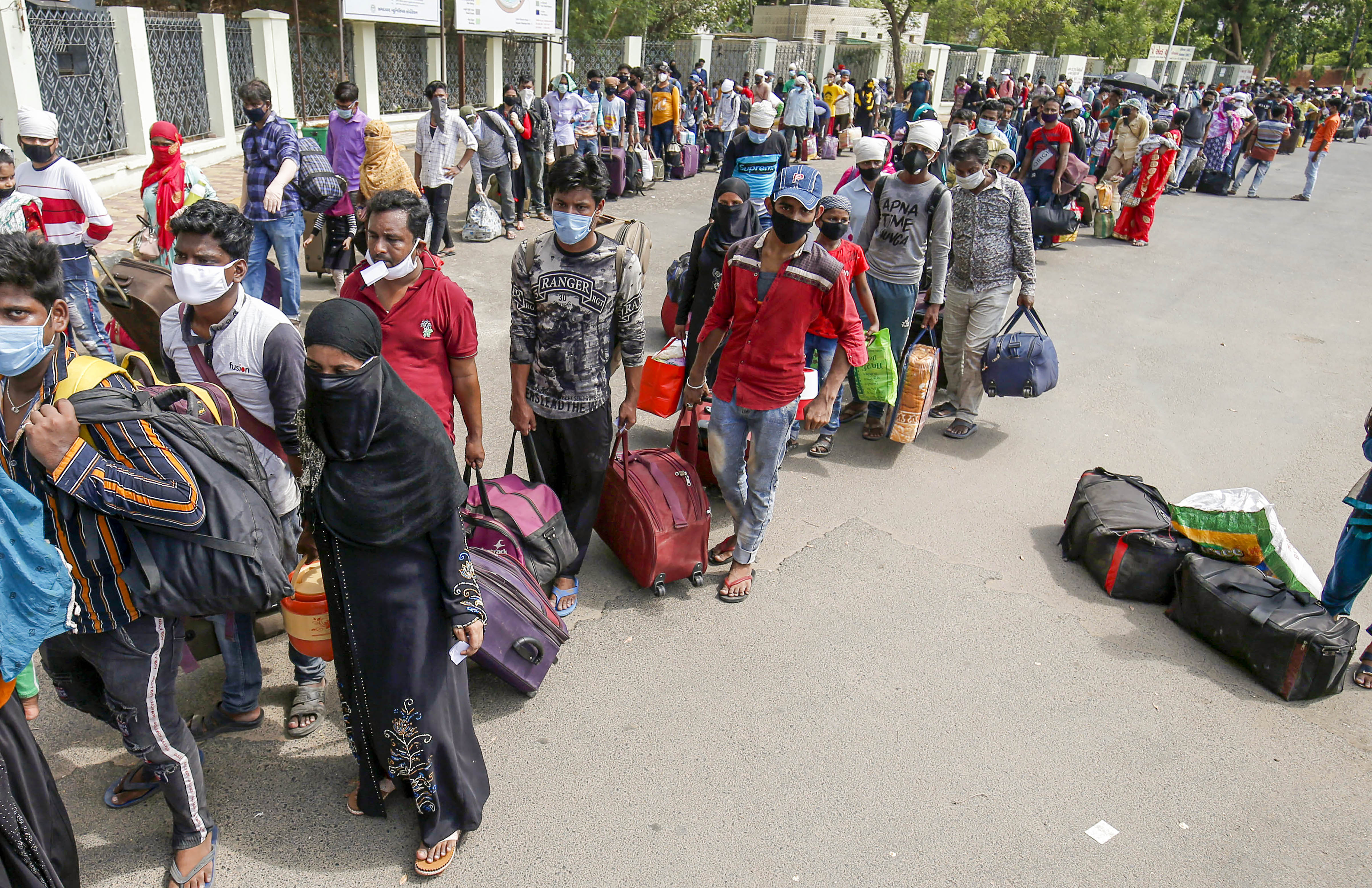 Migrants stand in queues as they wait to get on a bus for a railway station, where they will board a train to West Bengal, during the fifth phase of Covid-19 lockdown, in Ahmedabad, Friday, June 5, 2020.