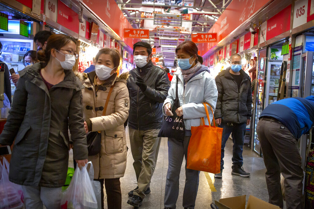 People wear face masks as they shop at a market in Beijing, Saturday, March 14, 2020.