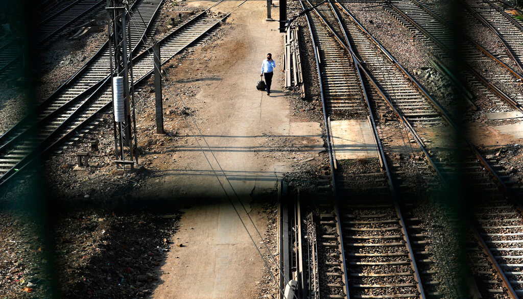 A man walks between railway tracks at New Delhi railway station during the lockdown on Monday