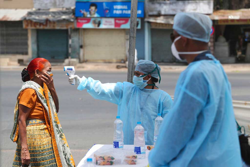 In this April 8, 2020, file photo, a health worker checks a woman's temperature during the nationwide lockdown in Ahmedabad.