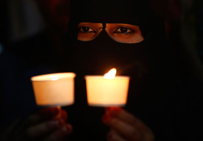 A Muslim woman holds candles during a protest against the sedition case filed by police against a school after a play performed by students denouncing a new citizenship law, in Bangalore, India on Tuesday