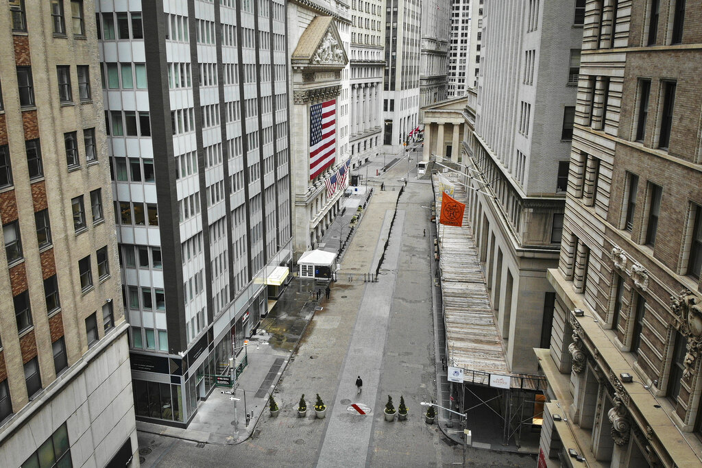A lone pedestrian wearing a protective mask walks past the New York Stock Exchange as COVID-19 concerns empty a typically bustling downtown area, Saturday, March 21, 2020, in New York. New York Gov. Andrew Cuomo announced sweeping orders Friday that will severely restrict gatherings of any size for the state's more than 19 million residents and will require workers in nonessential businesses to stay home.