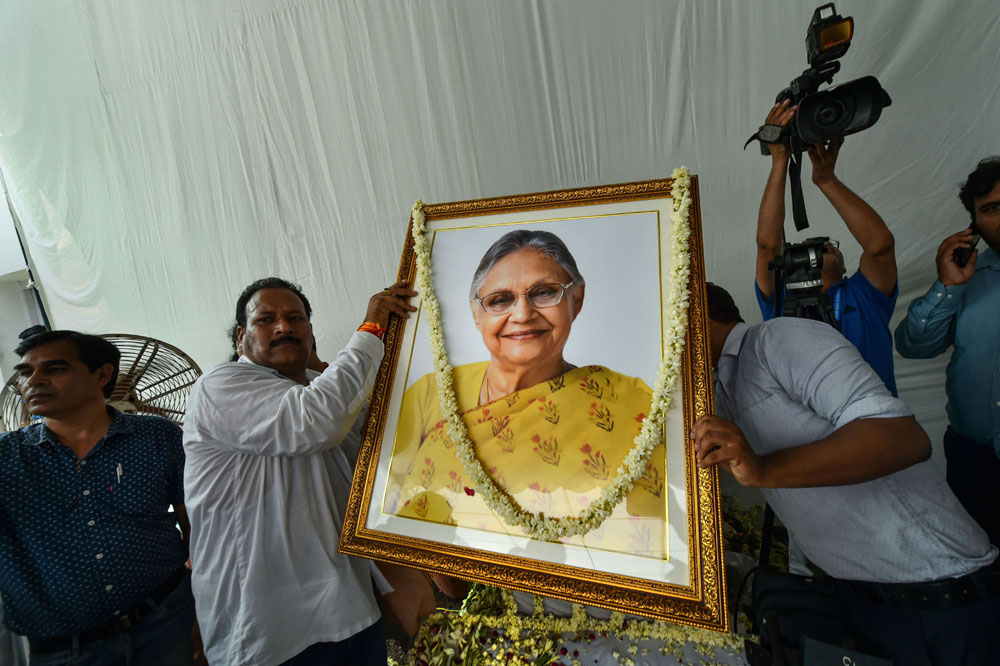 Supporters hold a portrait of former Delhi chief minister Sheila Dikshit while paying their last respects to her at the AICC headquarters in New Delhi, Sunday, July 21, 2019.
