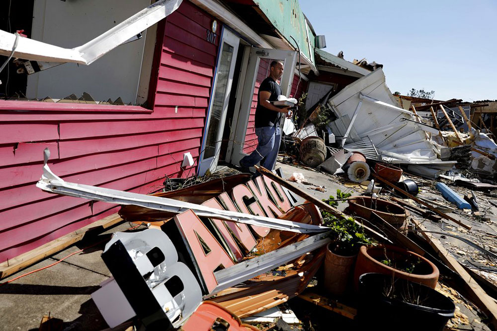 A man carries out items he salvaged from the damaged Thai restaurant he owns in the aftermath of hurricane Michael