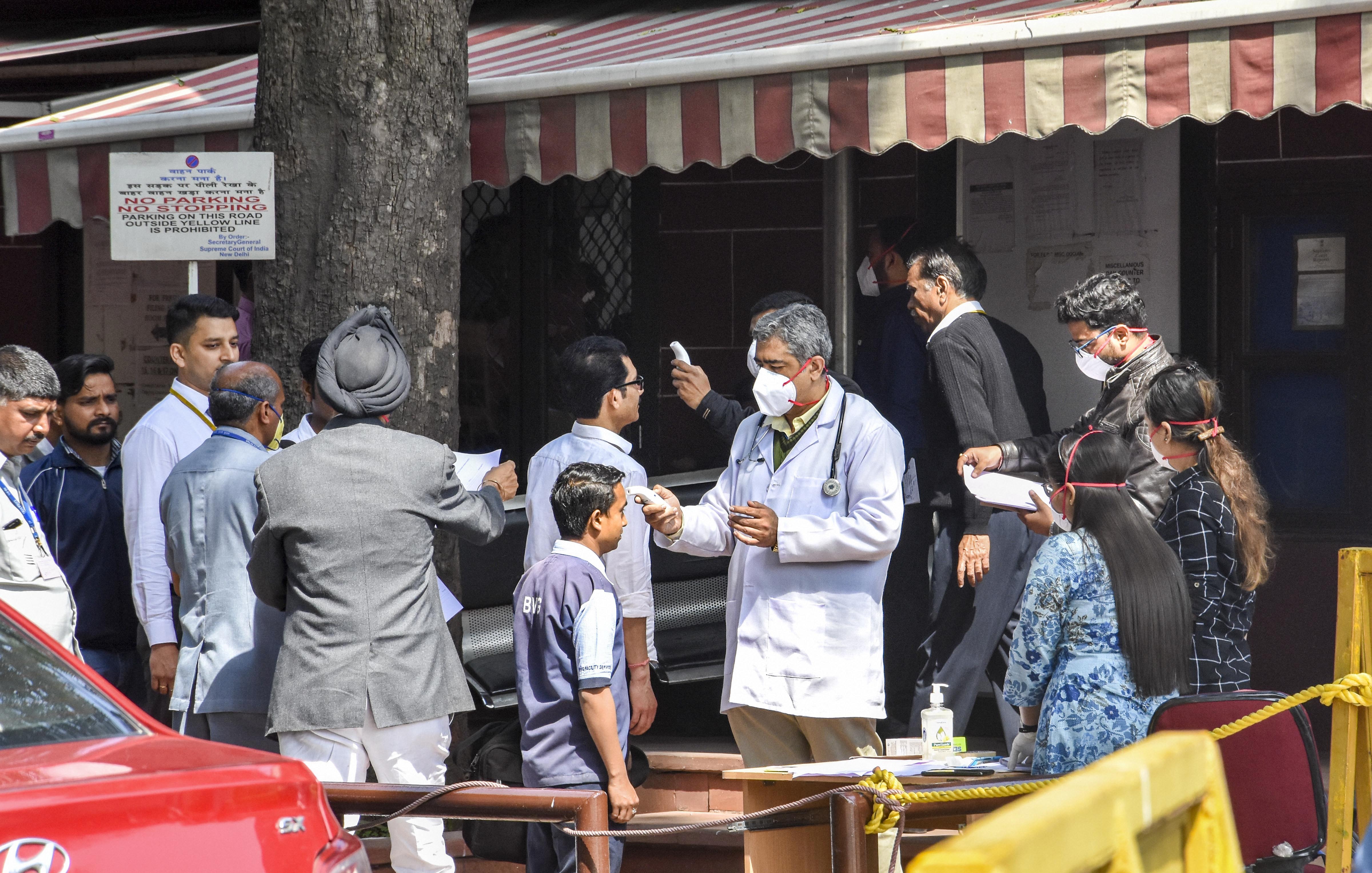 Members of Delhi government health department use screening devices on visitors in the wake of coronavirus, at the entrance of Supreme Court in New Delhi, Monday, March 16, 2020