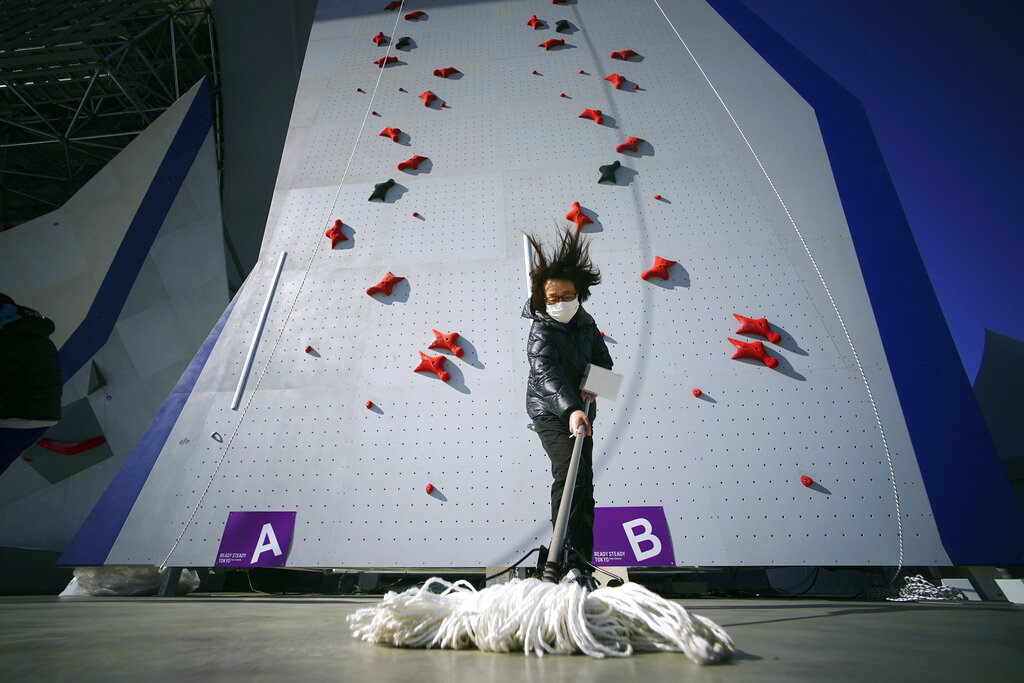 A Tokyo 2020 Olympic Games Organizing staff mops the floor in front of the climbing wall in the test event of Speed Climbing in preparation for the Tokyo 2020 Olympic Games at Aomi Urban Sports Park on Friday, March 6, 2020, in Tokyo. The recent outbreak of the coronavirus has forced them to cancel or postpone several. But they allowed a sport climbing event on Friday to go ahead, with a few restrictions: like the absence of elite athletes.