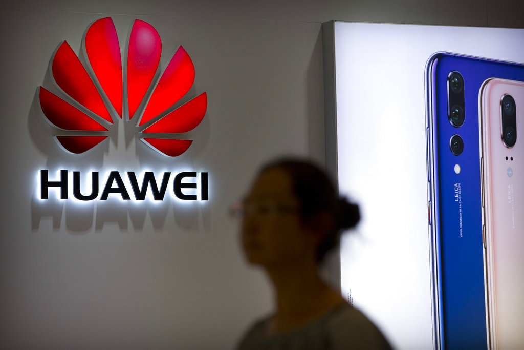 In this July 4, 2018, file photo, a shopper walks past a Huawei store at a shopping mall in Beijing. 