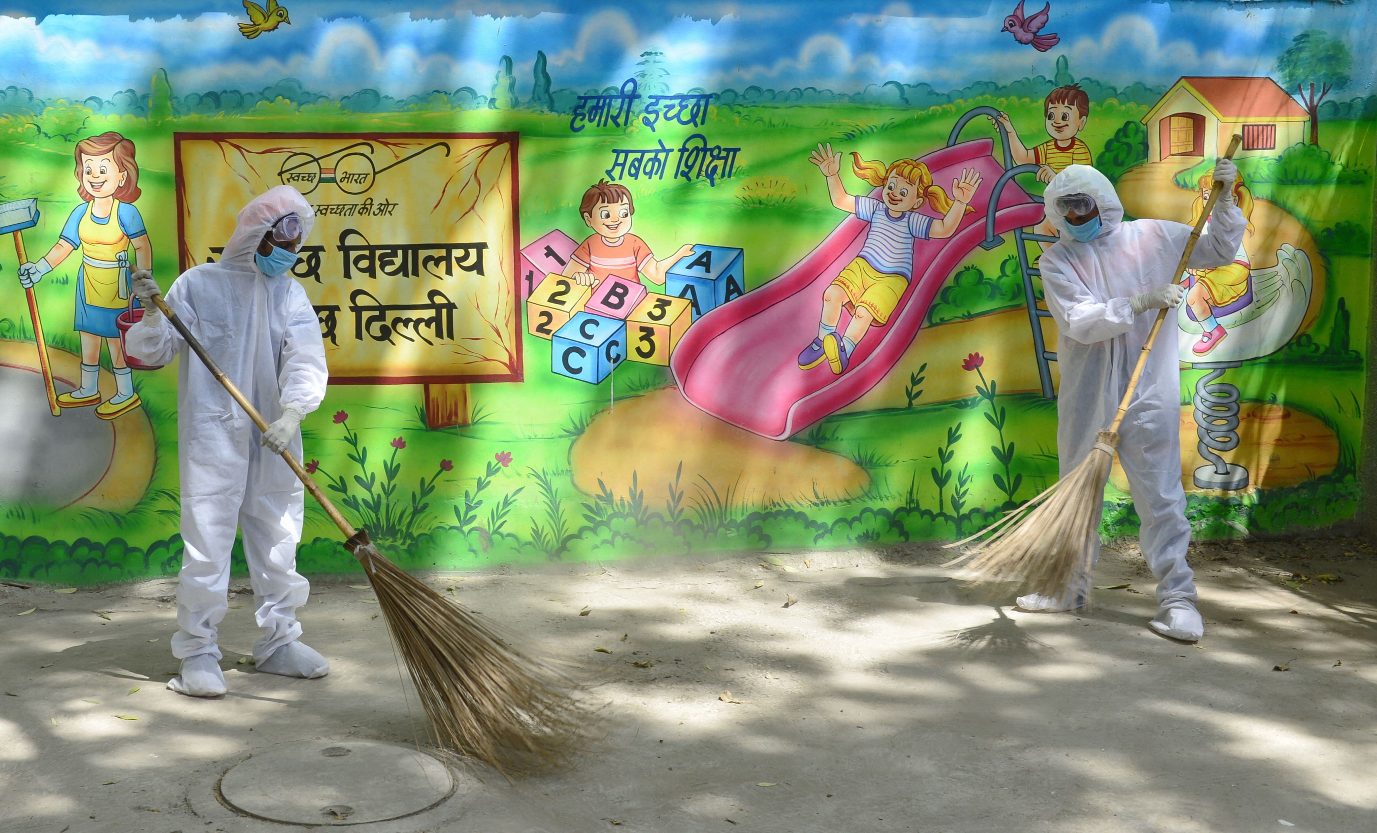 Sweepers wearing protective suits clean an area of a school during a nationwide lockdown as a preventive measure against the coronavirus pandemic, in New Delhi, Wednesday, April 22, 2020