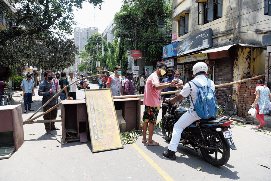 A resident of Ranikuthi stops a policeman at a blockade set up to protest the delay in resumption of power and water supply.