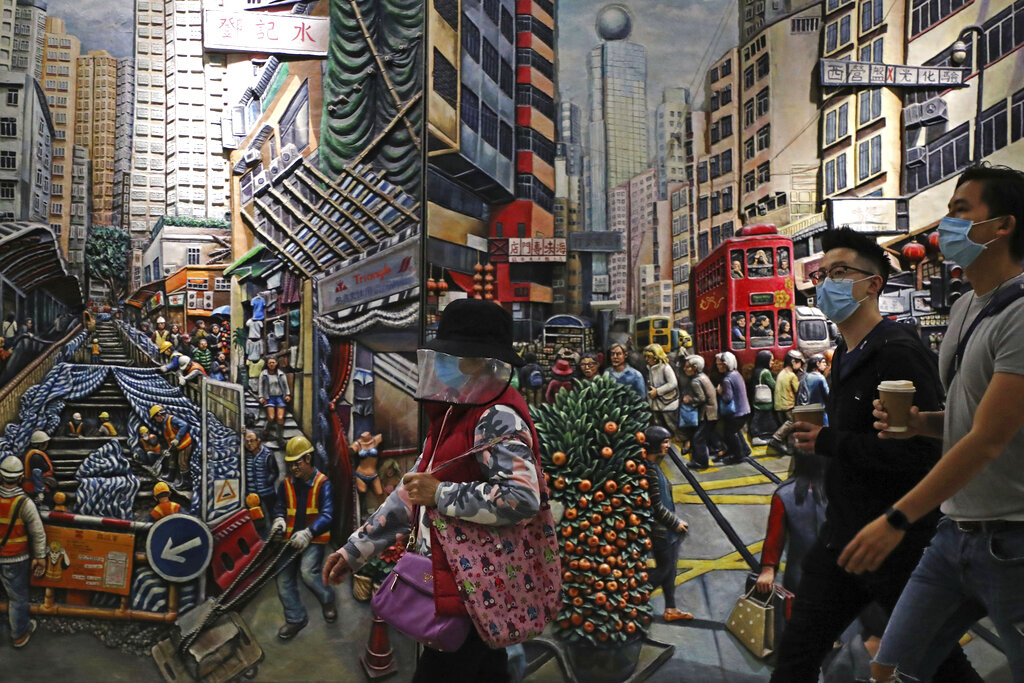 People wearing face masks to protect themselves from possibly contracting the coronavirus COVID-19 as they walk past a painting in Hong Kong, Saturday, April 25, 2020.