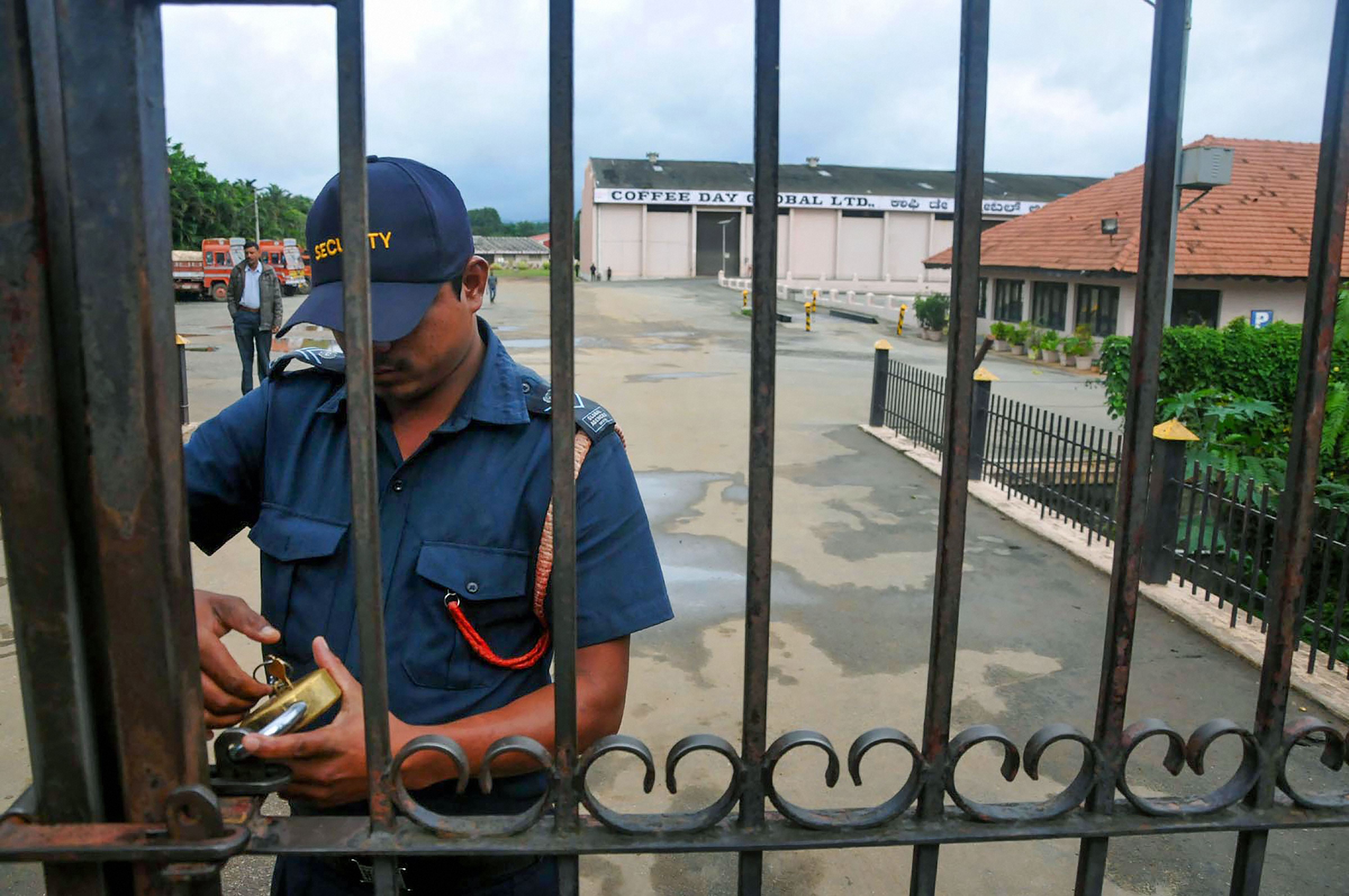 A security guard locks the gate of Coffee Day Company after the news of the disappearance of its owner and founder V.G. Siddhartha was reported in Chikmagalur on July 29.