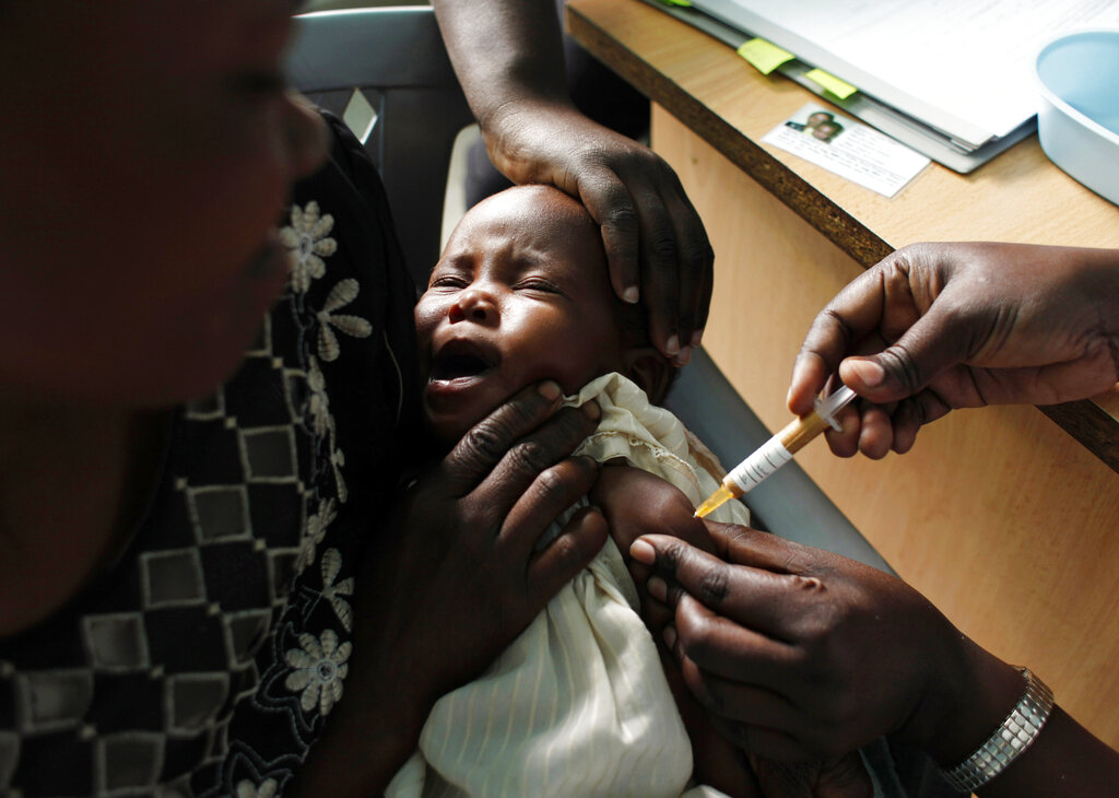 In this Oct. 30, 2009 file photo, a mother holds her baby receiving a new malaria vaccine as part of a trial at the Walter Reed Project Research Center in Kombewa in Western Kenya. 