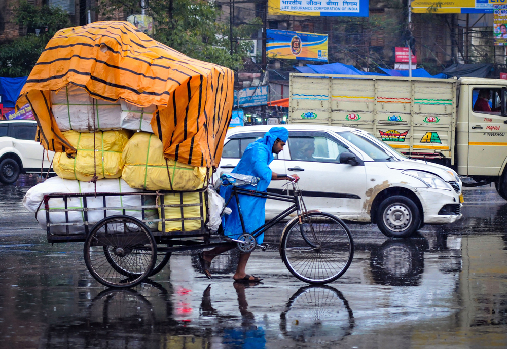 A man pulls a tricycle wearing a raincoat on a wet, wintery day in Calcutta on January 3