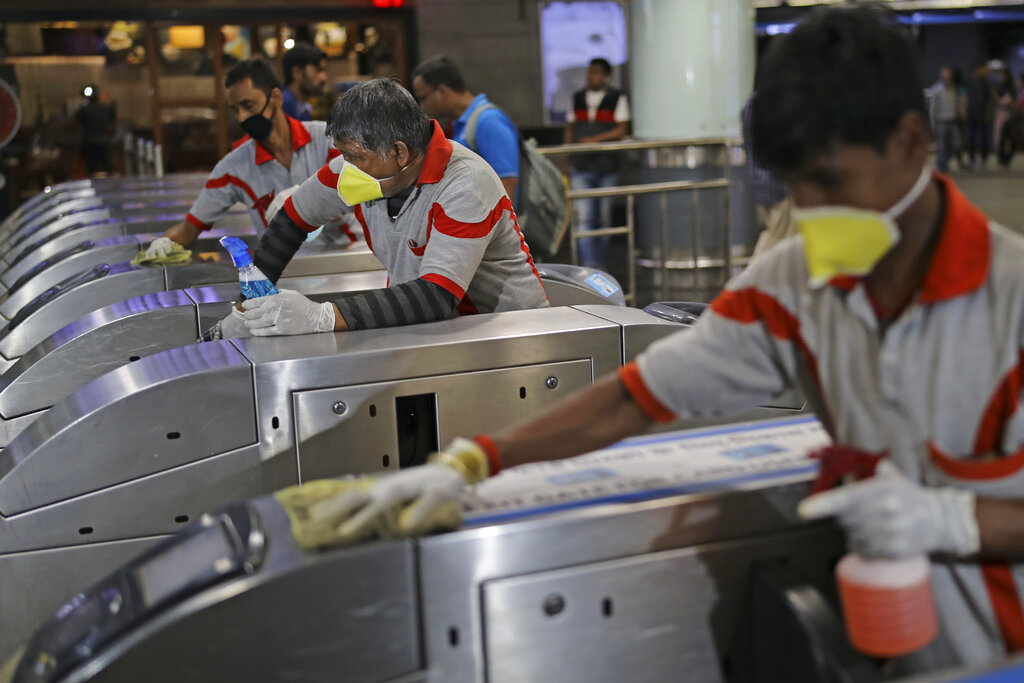 Workers disinfect the gates as a precaution against COVID-19 at a metro station in New Delhi, on Friday, March 13, 2020. According to the World Health Organization, people with mild illness recover in about two weeks, while those with more severe illness may take three to six weeks to recover.