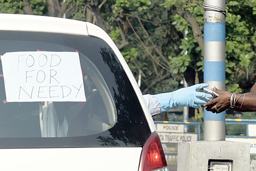 A man hands a food packet to a woman in the Babughat area on Friday afternoon. The man is part of a group from Kidderpore that distributed food packets to over 500 people during the day in the Hastings, Prinsep Ghat, 
Red Road, Babughat and SSKM Hospital areas