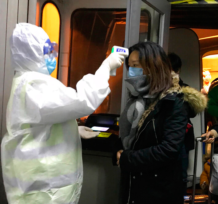 Health Officials in hazmat suits check body temperatures of passengers arriving from the city of Wuhan