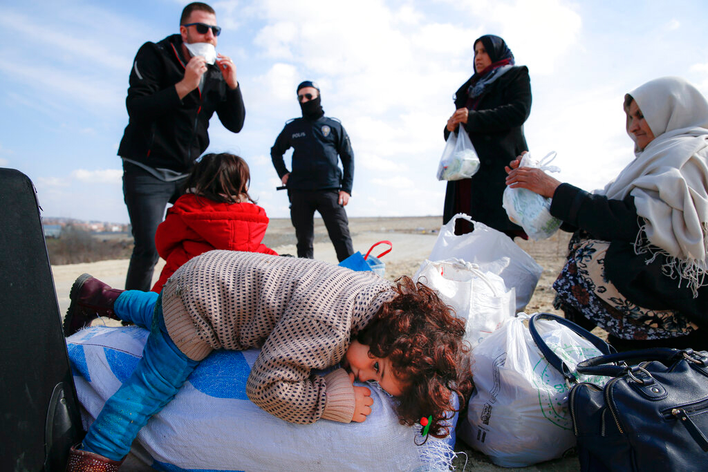 A child lies on a sack with belongings as migrants rest on their way to Greece in Edirne, Turkey, on March 1