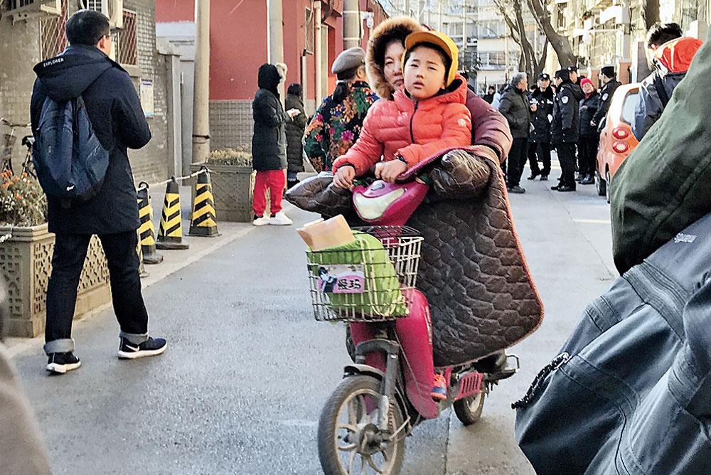A woman and her child leave the Beijing No. 1 Affiliated Elementary School after the attack on Tuesday. 

