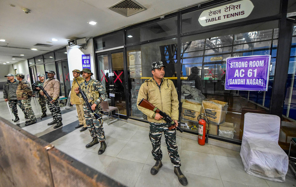 Security personnel stand guard outside a strong room, a day after national capital went to polls for the Assembly election, at a counting centre in Akshardham, New Delhi